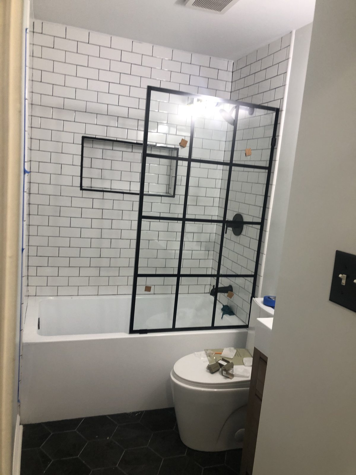 White subway tub surround with black grid glass