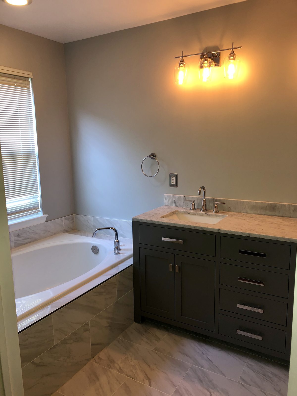 Soaking tub with marble surround and gray vanity