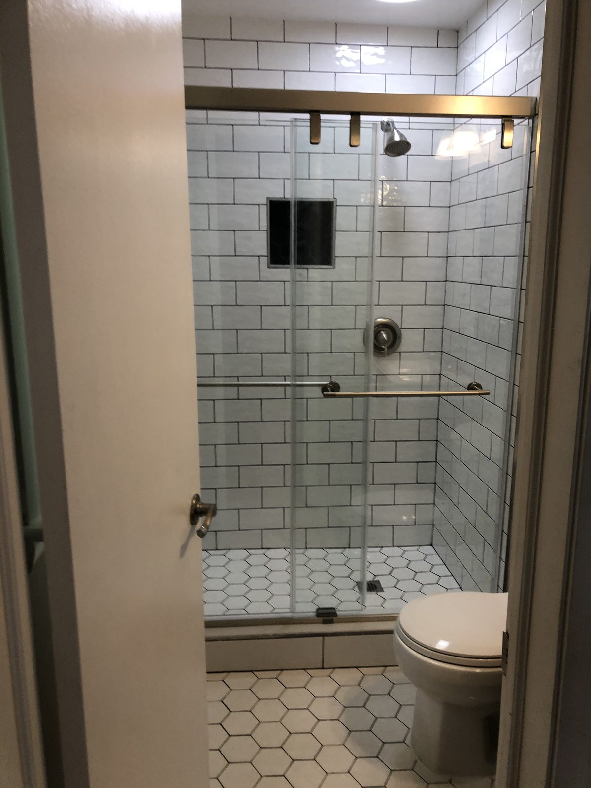 Subway tile shower with brushed gold trim
