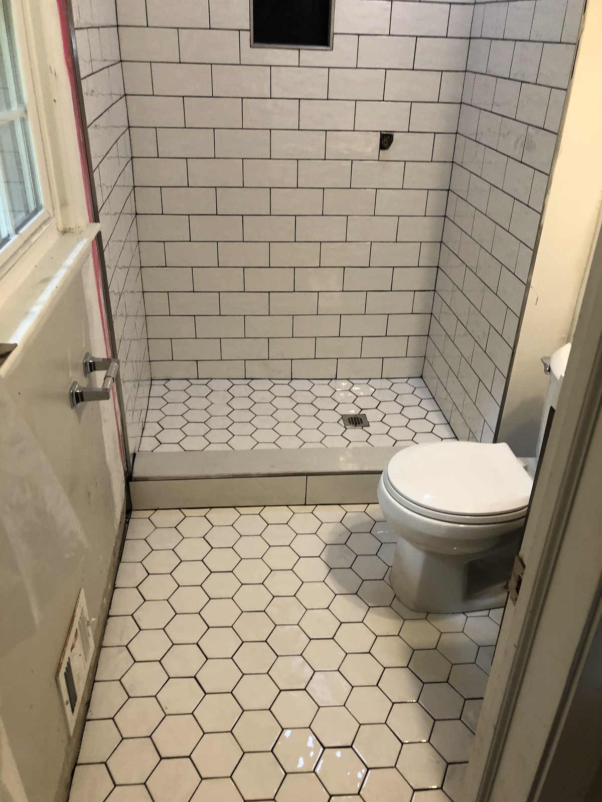White subway tile shower with hex floor