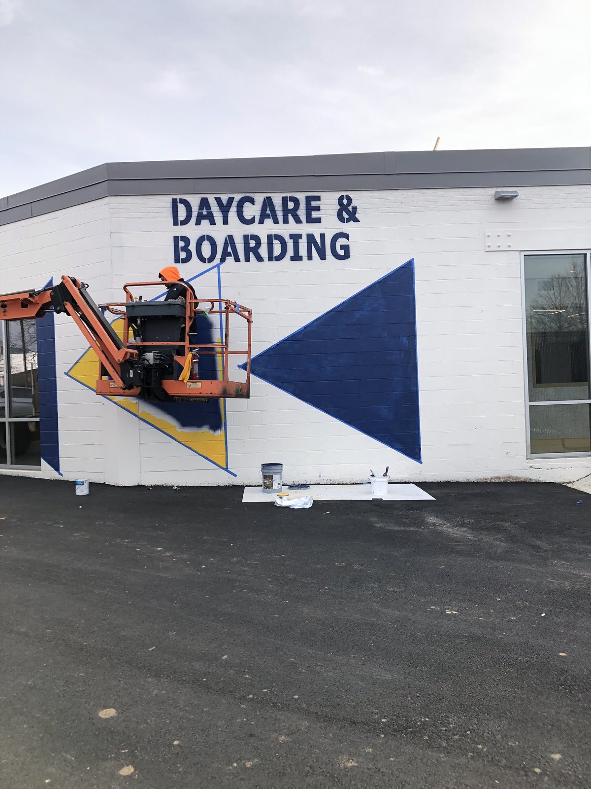 Boom lift painting a large commercial wall